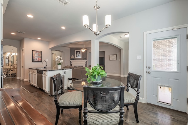 dining area with ceiling fan with notable chandelier, dark wood-type flooring, and sink