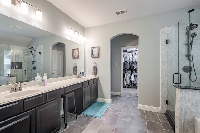 bathroom with tile patterned flooring, a shower with door, and vanity