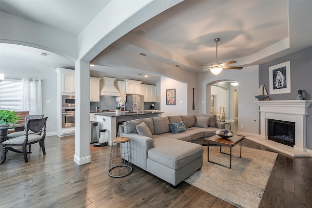 living room featuring ceiling fan and dark wood-type flooring