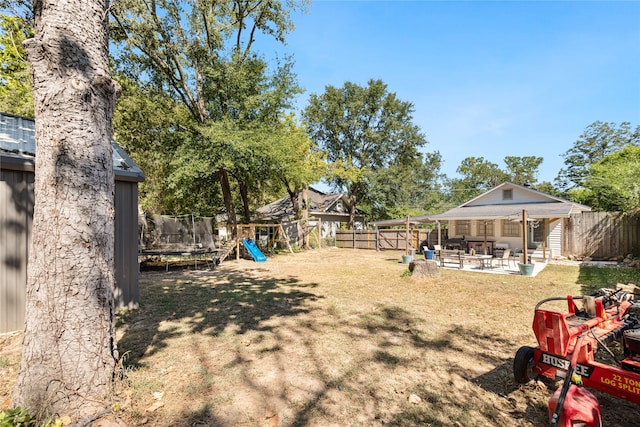 view of yard featuring a trampoline, a playground, and a patio