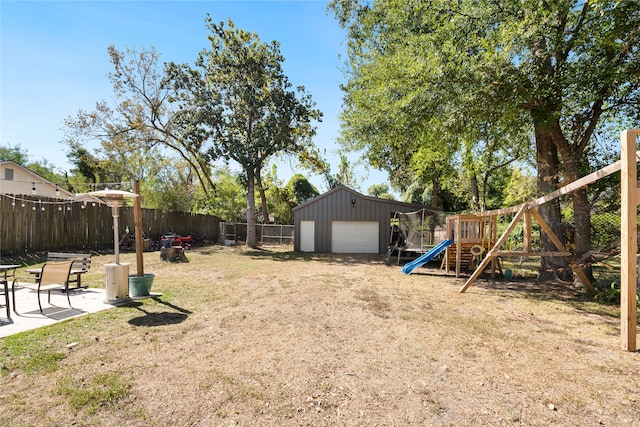 view of yard featuring a playground, a garage, a patio area, and an outbuilding