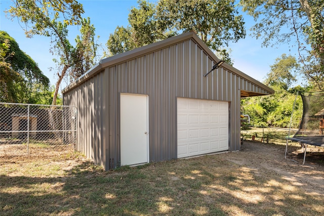 garage with a lawn and a trampoline