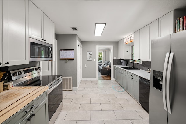 kitchen with light tile patterned floors, sink, white cabinetry, gray cabinets, and appliances with stainless steel finishes