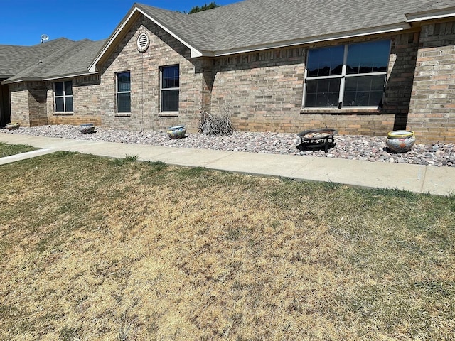 back of property featuring roof with shingles and a yard