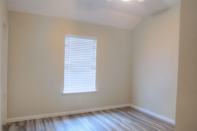 spare room featuring lofted ceiling and light hardwood / wood-style floors