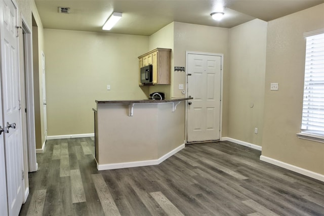 kitchen with dark wood-style flooring, visible vents, a breakfast bar, dark countertops, and black microwave