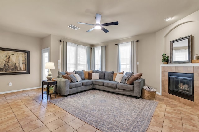 tiled living room featuring a tiled fireplace and ceiling fan