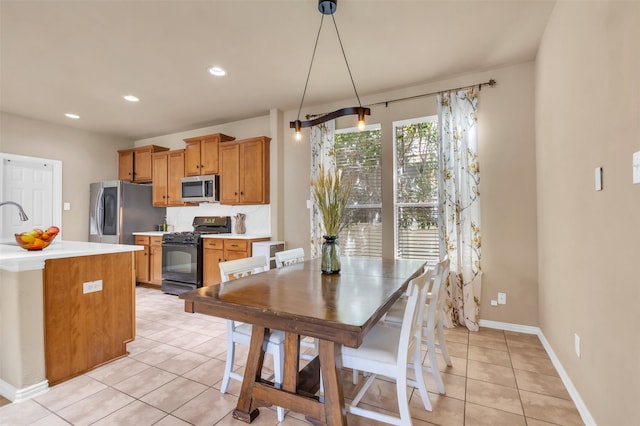 kitchen with decorative light fixtures, a kitchen island, light tile patterned floors, and appliances with stainless steel finishes