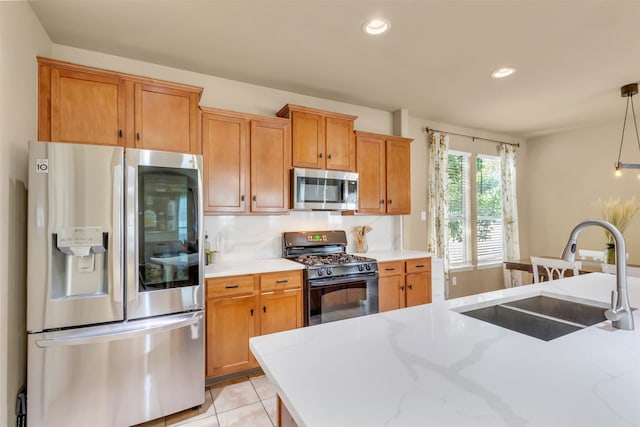 kitchen featuring tasteful backsplash, stainless steel appliances, sink, pendant lighting, and light tile patterned flooring