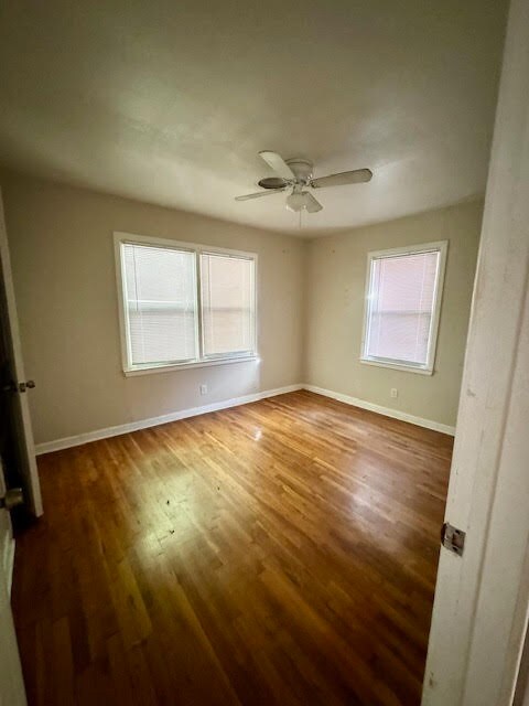 empty room featuring ceiling fan, dark hardwood / wood-style floors, and a wealth of natural light