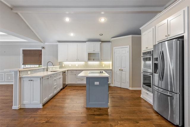 kitchen featuring white cabinets, appliances with stainless steel finishes, a kitchen island, vaulted ceiling with beams, and kitchen peninsula