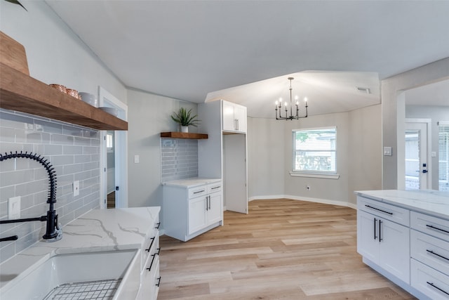 kitchen featuring sink, a chandelier, white cabinetry, light wood-type flooring, and decorative backsplash