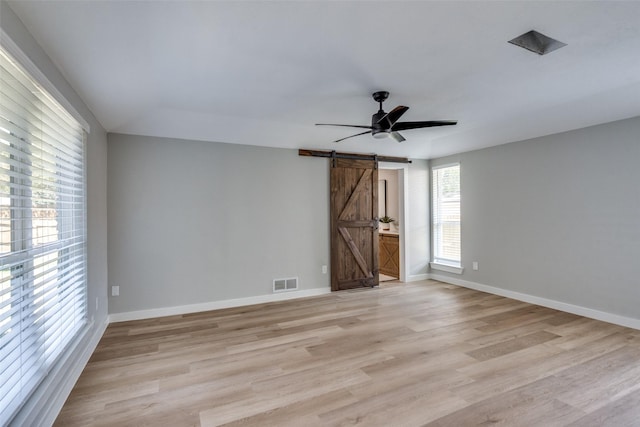 2625 Mollimar Dr, Plano, TX 75075 - empty room featuring a barn door, light wood finished floors, baseboards, visible vents, and a ceiling fan
