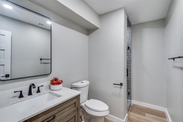 bathroom featuring vanity, hardwood / wood-style floors, toilet, and a shower with shower door