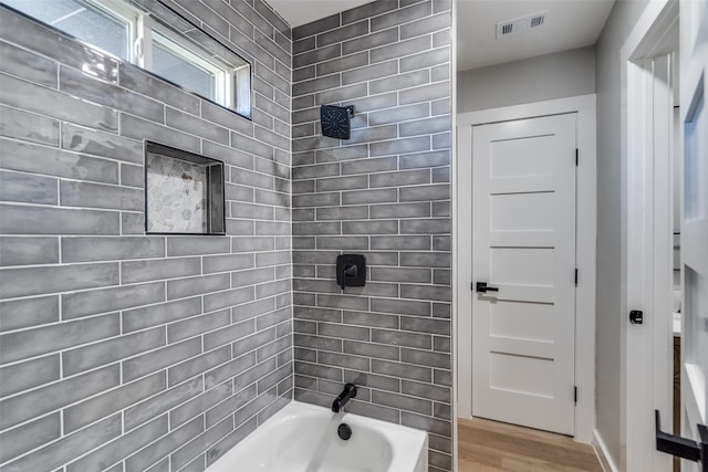 bathroom with tiled shower / bath combo and hardwood / wood-style floors