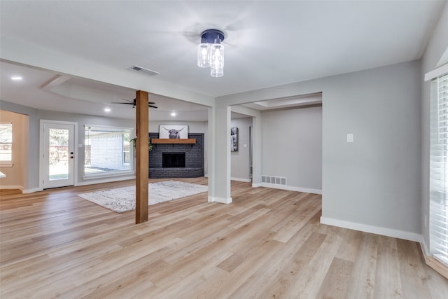 unfurnished living room featuring a brick fireplace, light wood-type flooring, and ceiling fan