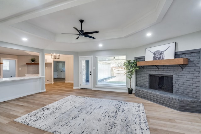 2625 Mollimar Dr, Plano, TX 75075 - living room with a fireplace, light wood-type flooring, a tray ceiling, and ceiling fan with notable chandelier