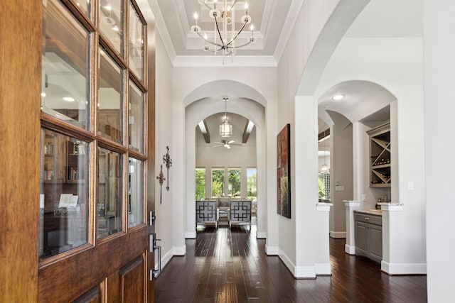 entrance foyer with ceiling fan with notable chandelier, crown molding, and dark hardwood / wood-style flooring