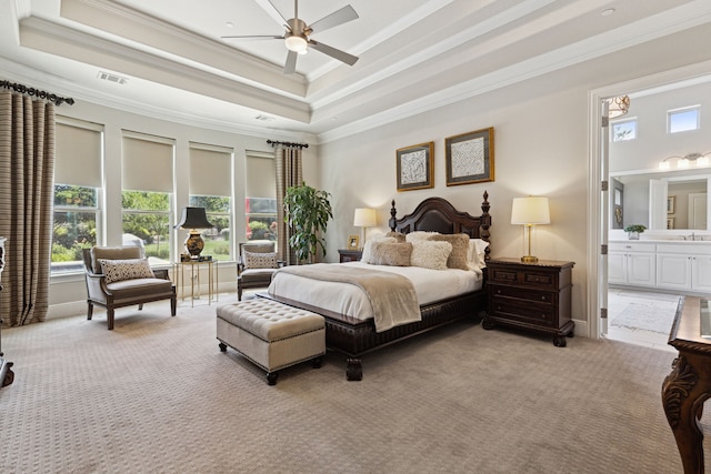 carpeted bedroom featuring a tray ceiling, a towering ceiling, ensuite bathroom, ornamental molding, and ceiling fan