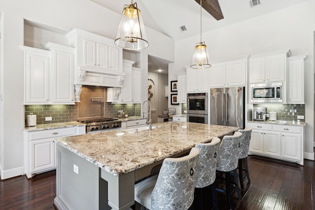 kitchen with stainless steel appliances, white cabinets, dark hardwood / wood-style floors, and a kitchen island with sink