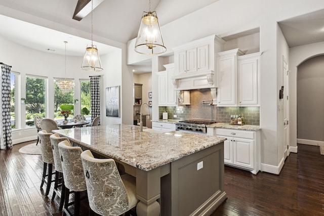 kitchen featuring an island with sink, hanging light fixtures, dark hardwood / wood-style floors, and white cabinetry