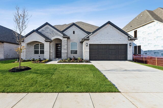 french provincial home with a front yard and a garage