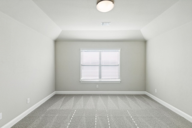 carpeted spare room featuring vaulted ceiling