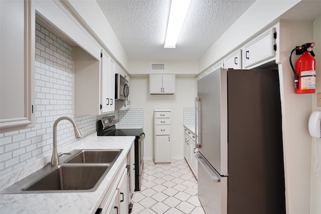 kitchen featuring backsplash, white cabinetry, sink, and appliances with stainless steel finishes