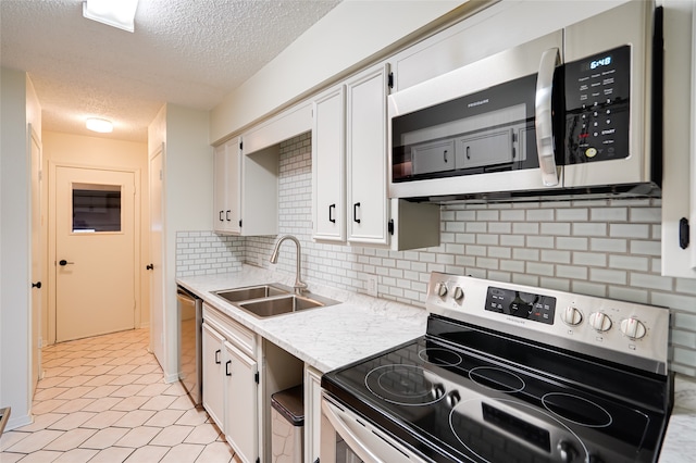 kitchen featuring stainless steel appliances, white cabinetry, tasteful backsplash, and sink