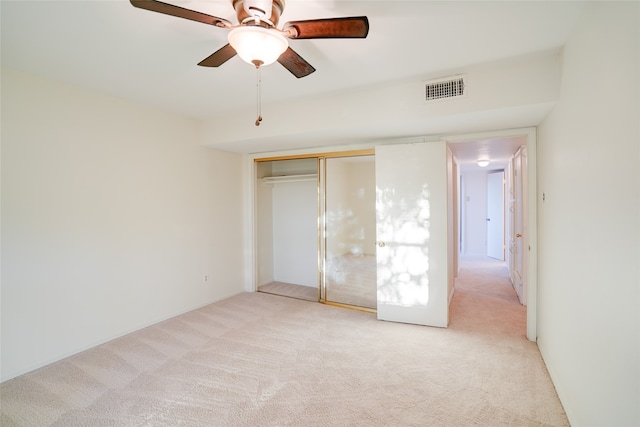 unfurnished bedroom featuring a ceiling fan, visible vents, a closet, and light colored carpet