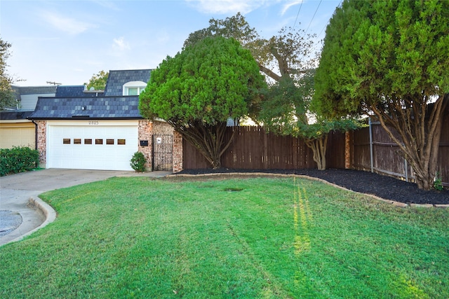 view of yard with driveway, an attached garage, and fence