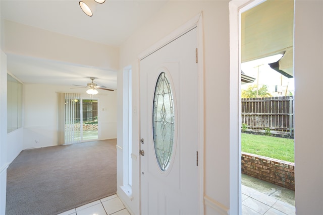 carpeted entrance foyer with ceiling fan and a healthy amount of sunlight