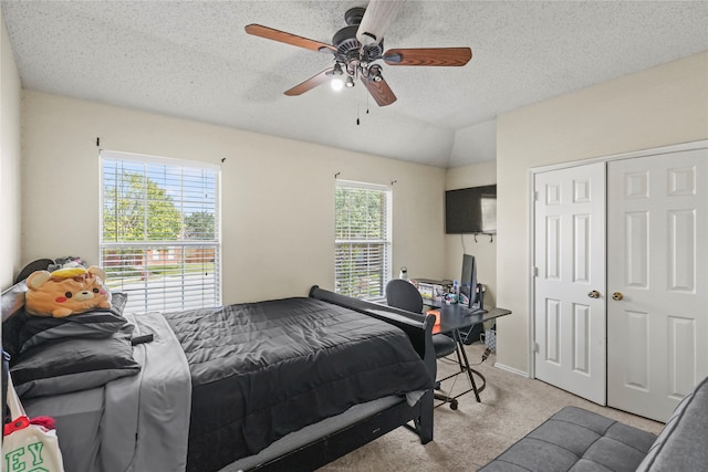 carpeted bedroom featuring ceiling fan, a textured ceiling, and multiple windows