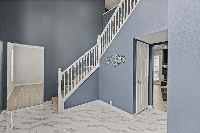 stairway with wood-type flooring, a towering ceiling, and ceiling fan