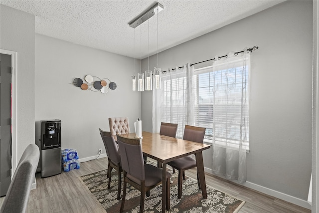 dining space with a textured ceiling and light hardwood / wood-style floors