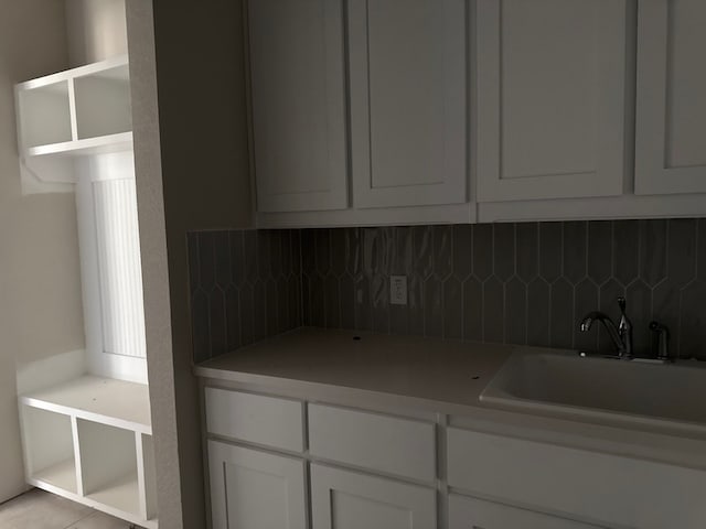 kitchen featuring white cabinets, light tile patterned floors, sink, and tasteful backsplash