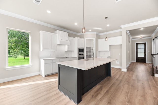 kitchen featuring premium range hood, a sink, a large island, white cabinets, and appliances with stainless steel finishes