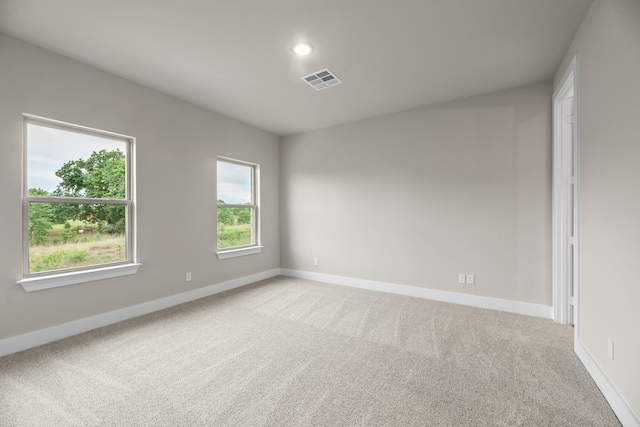 spare room featuring light colored carpet, baseboards, and visible vents