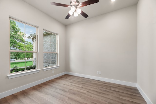 unfurnished room with baseboards, a wealth of natural light, light wood-style floors, and a ceiling fan