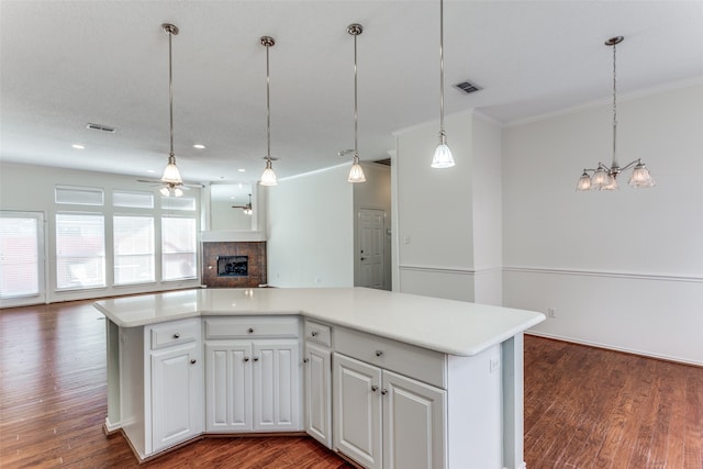 kitchen with white cabinets, decorative light fixtures, a kitchen island, and dark hardwood / wood-style flooring