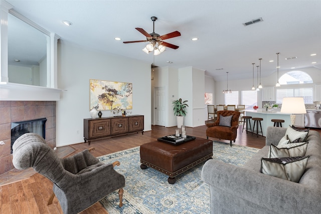 living room with hardwood / wood-style flooring, a tile fireplace, and ceiling fan