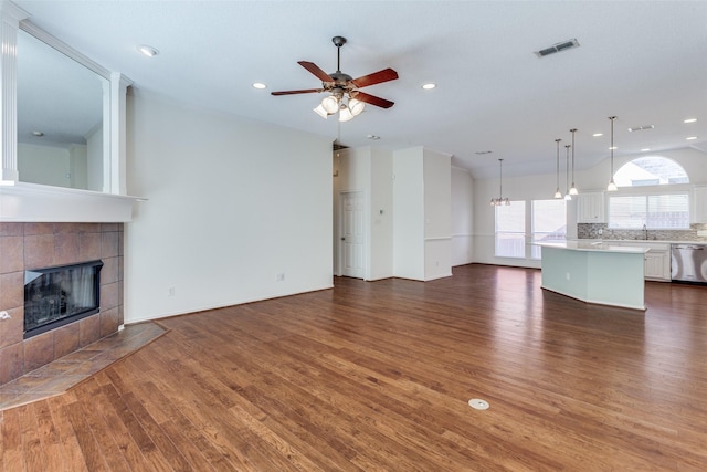 7128 White Tail Trl, Fort Worth, TX 76132 - unfurnished living room featuring a sink, a fireplace, visible vents, wood finished floors, and ceiling fan with notable chandelier