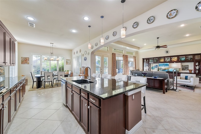 kitchen with dark brown cabinets, a healthy amount of sunlight, dark stone countertops, and sink