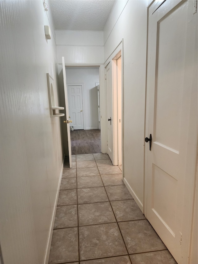 corridor with tile patterned flooring and a textured ceiling