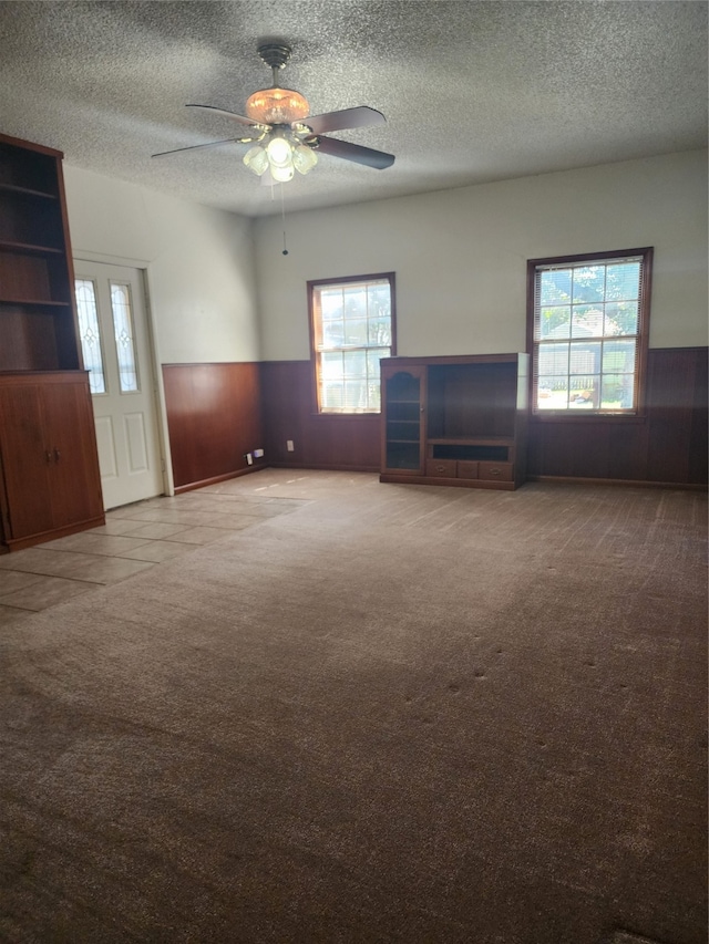 unfurnished living room featuring ceiling fan, a textured ceiling, carpet flooring, and a healthy amount of sunlight