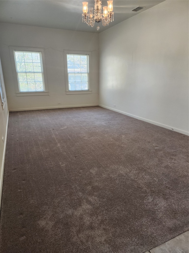 carpeted spare room with an inviting chandelier