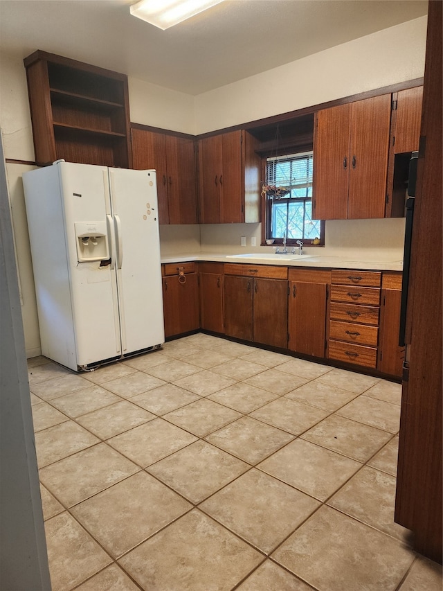 kitchen featuring light tile patterned floors, white refrigerator with ice dispenser, and sink