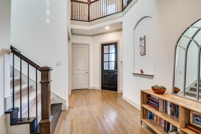 entryway featuring ornamental molding, light hardwood / wood-style floors, and a high ceiling