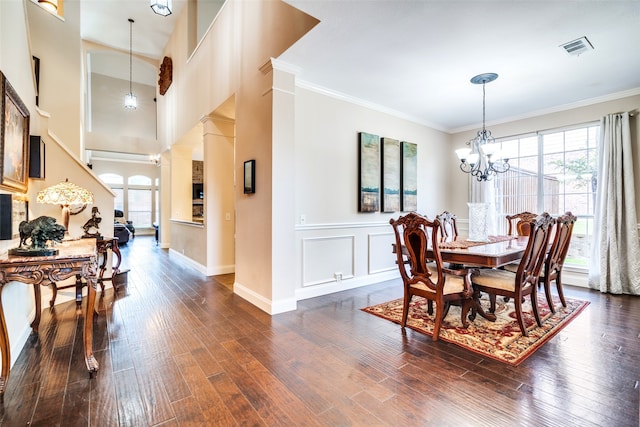 dining room with a chandelier, dark hardwood / wood-style flooring, decorative columns, and crown molding