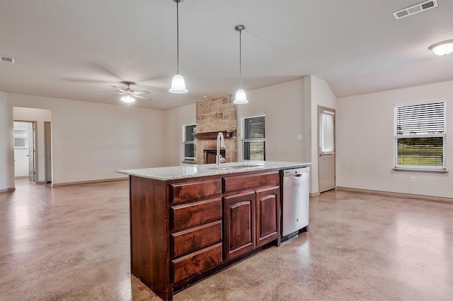 kitchen featuring an island with sink, sink, stainless steel dishwasher, a stone fireplace, and decorative light fixtures